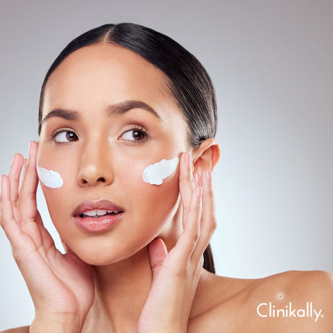 Woman applying shea butter cream to the face