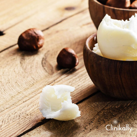 Raw shea butter with shea nuts on a wooden spoon