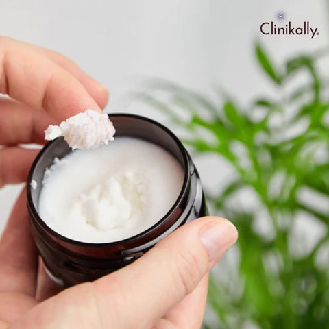 Hand scooping shea butter from a skincare cream jar
