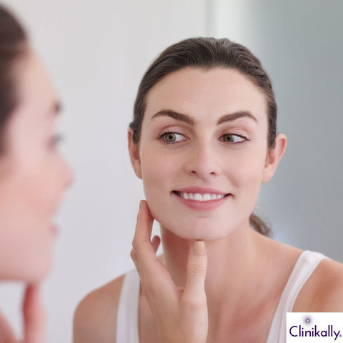 Woman admiring healthy glowing skin in mirror after OTZ 10 skincare routine